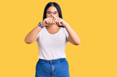 Genç ve güzel Asyalı kız günlük kıyafetler giyiyor ve gözlük takıyor. Reddedilme ifadesi negatif işaret veriyor. 