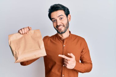 Elinde yemek tutan genç İspanyol adam gülümseyerek el ve parmağıyla işaret ediyor. 