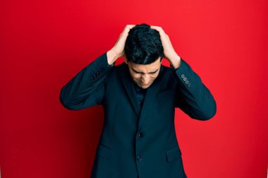 İş kıyafetleri giyen yakışıklı İspanyol adam. Baş ağrısı, acı ve migren yüzünden çaresiz ve stresli. Eller başının üstünde.. 