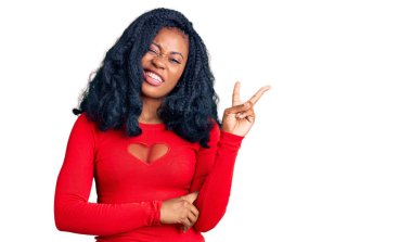 Güzel Afro-Amerikan kadın, günlük kıyafetler giyip kameraya gülümseyen ve zafer işareti yapan. İki numara.. 