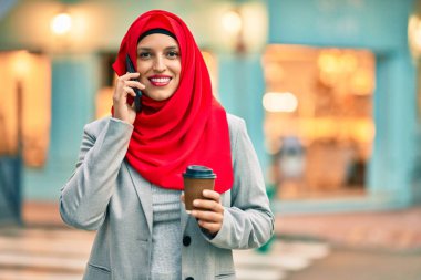 Genç Arap iş kadını akıllı telefondan konuşuyor ve şehirde kahve içiyor..