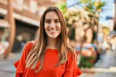 Genç İspanyol kadın gülümseyerek şehirde mutlu mesut dikiliyor..