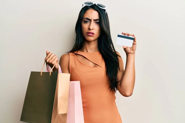 Schöne Hispanische Frau Mit Einkaufstaschen Und Kreditkarte Ahnungslos Und Verwirrt — Stockfoto