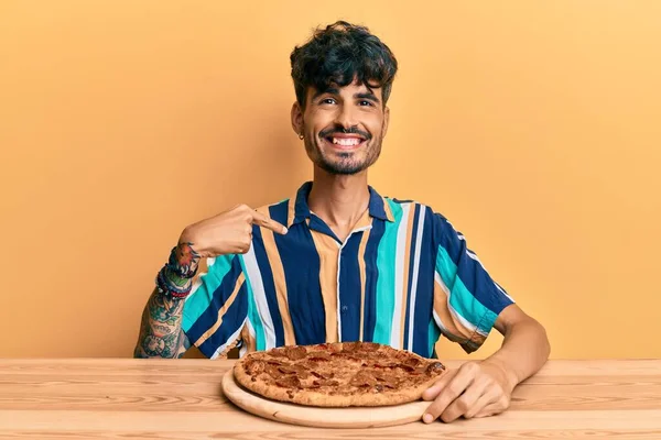 스페인 남자가 식탁에 이탈리아 피자를 먹으면서 행복하고 자랑스럽게 미소짓고 자신을 — 스톡 사진