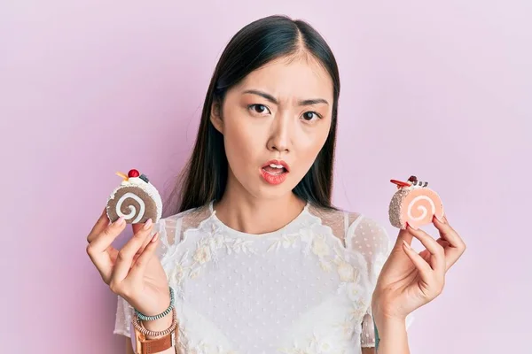 Joven Mujer China Sosteniendo Dulces Pastel Cara Choque Mirando Escéptico — Foto de Stock