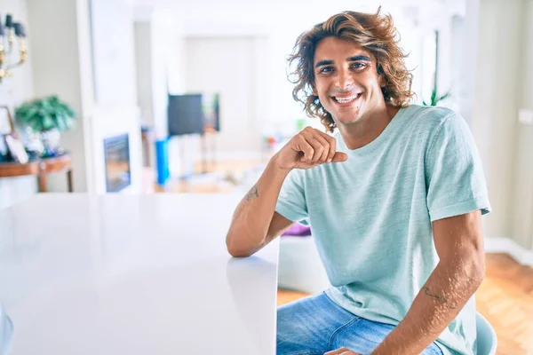 Joven Hombre Hispano Sonriendo Feliz Sentado Mesa Casa —  Fotos de Stock