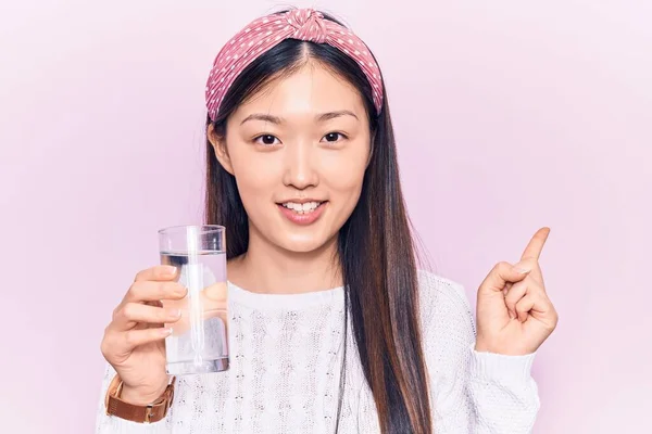 Νεαρή Όμορφη Κινέζα Γυναίκα Πίνει Ποτήρι Νερό Χαμογελώντας Χαρούμενη Δείχνοντας — Φωτογραφία Αρχείου