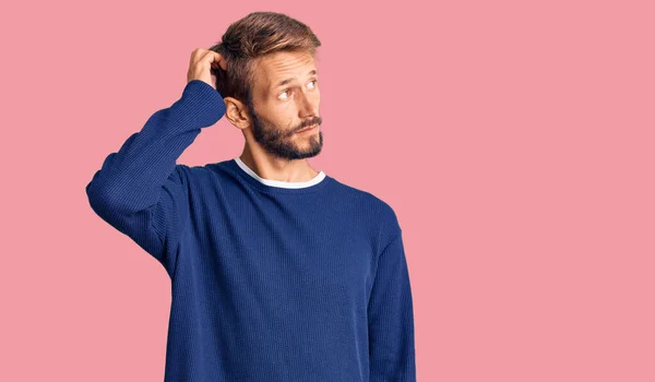 カジュアルなセーターを着てひげを生やしたハンサムなブロンドの男は混乱し 疑問に思っています 疑いもなく頭に手を置いて考える 包括的な概念は — ストック写真