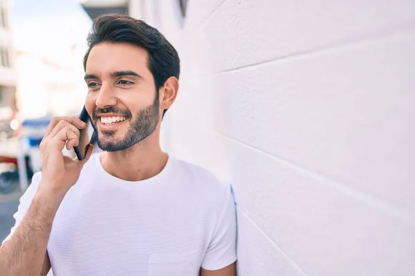 Молодий Іспаномовний Чоловік Посміхається Щасливим Розмовляти Смартфоні Спираючись Стіну — стокове фото
