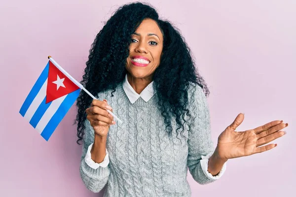 幸せな笑顔で達成を祝うキューバフラグを保持する中世アフリカ系アメリカ人女性と手を上げと勝者の式 — ストック写真