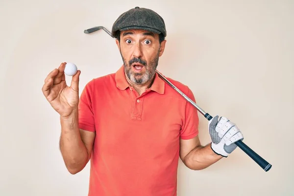 Medelålders Latinamerikan Håller Golfklubba Och Boll Ledtrådar Och Förvirrade Uttryck — Stockfoto