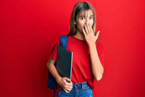 10代の白人の女の子学生のバックパックを着て 手で口をカバーし コンピュータのラップトップを保持し ショックを受け ミスを恐れている 驚きの表情 — ストック写真