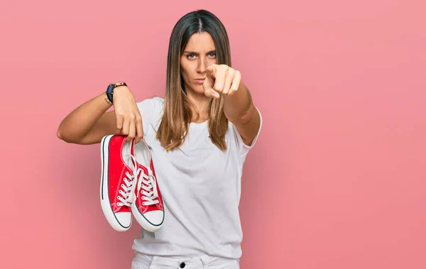 Mujer Joven Sosteniendo Zapatos Casuales Rojos Señalando Con Dedo Cámara —  Fotos de Stock