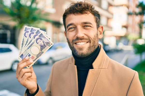 エレガントなジャケットを着たハンサムなビジネスマンが屋外で幸せな笑顔を見せ 5000円の紙幣を見せます — ストック写真