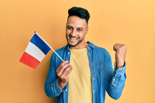 フランスの旗を持っている若いアラブ人の男は誇りに思って叫んで 勝利と成功を祝う非常に興奮して腕を上げ — ストック写真