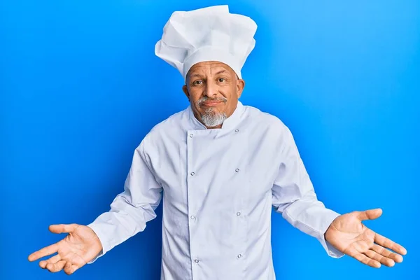 中年白发男子身穿职业厨师制服 头戴无头无脑的帽子 满脸困惑 手臂和双手高举 怀疑概念 — 图库照片