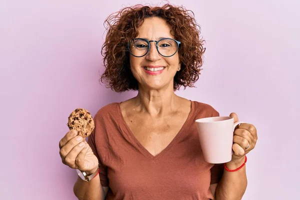 美しい中年の熟女がコーヒーを飲み クッキーは笑顔で幸せとクールな笑顔で笑っています 歯を見せて — ストック写真