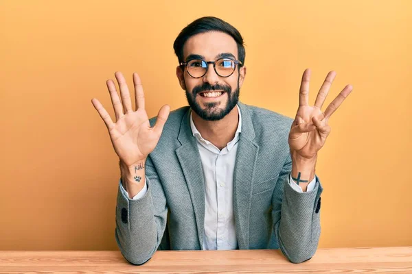 自信と幸せ笑いながらオフィスで働いている若いヒスパニック系の男は指の数8を示し 指摘します — ストック写真