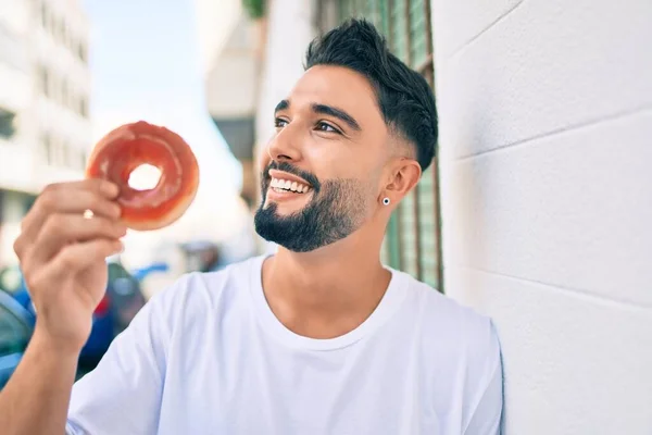 Jonge Arabier Man Glimlachend Gelukkig Vasthouden Donut Leunend Muur Stad — Stockfoto