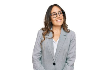 İş kıyafetleri giymiş genç esmer kadın yüzünde gülümsemeyle yan yana bakıyor, doğal bir ifade. Kendinden emin gülen. 
