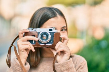 Genç İspanyol turist kadın şehirde klasik kamera kullanarak mutlu bir şekilde gülümsüyor..