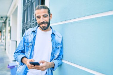 Ortadoğulu genç adam şehirde akıllı telefon kullanıyor..