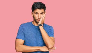 Gündelik kıyafetler giyen yakışıklı genç adam kollarını kavuşturarak depresyondan sıkılmış ve yorgun görünüyor.. 