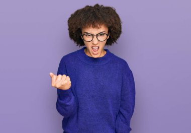 Kışlık süveter giyen, kızgın ve kızgın gözlüklü genç İspanyol kız öfkeyle bağırırken yumruk sallıyor ve öfkeliydi. öfke ve agresif konsept. 