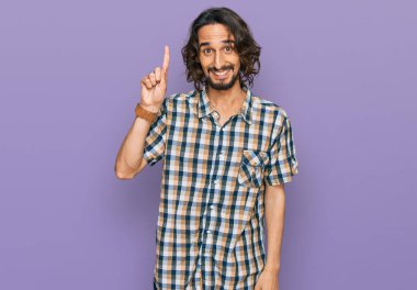 Gündelik kıyafetler giyen genç İspanyol adam başarılı bir fikirle işaret ediyor. Heyecanlı ve mutlu. Bir numara.. 