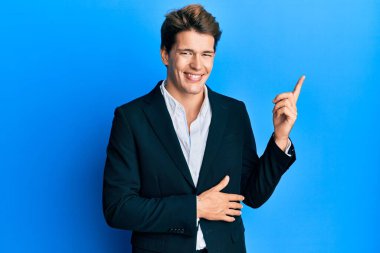 İş elbisesi ve kravat takan yakışıklı beyaz adam mutlu bir şekilde elini ve parmağını yana doğru uzattı. 