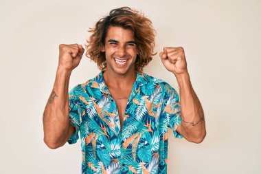 Yazlık tişört giyen İspanyol genç adam gururla bağırıyor, zaferi kutluyor ve başarıyı kollarını kaldırarak kutluyor. 