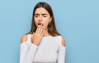 Günlük kıyafetler giyen genç İspanyol kadın ağzıyla ağzını kapatmaktan sıkılmış. Huzursuz ve uykulu.. 