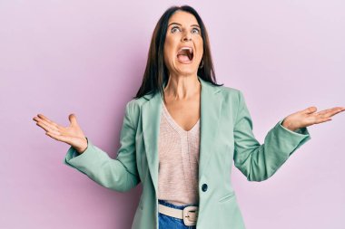 Orta yaşlı esmer kadın gündelik kıyafetler giyip deli gibi bağırıyor ve agresif bir ifade ve kollarla bağırıyor. hüsran kavramı. 