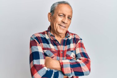 Günlük kıyafetler giyen, kollarını kavuşturup kameraya gülümseyen İspanyol kıdemli bir adam. pozitif kişi. 