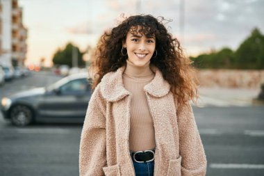 Genç İspanyol kadın gülümseyerek şehirde mutlu mesut dikiliyor.