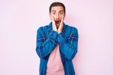 Gündelik kıyafetler giyen genç yakışıklı adam korkmuş ve şok olmuş, şaşırmış ve şaşırmış bir yüz ifadesi var. 