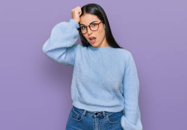 Young hispanic woman wearing casual clothes and glasses surprised with hand on head for mistake, remember error. forgot, bad memory concept.  clipart