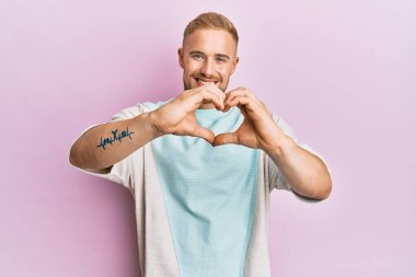 Gündelik kıyafetler giyen, aşık gülümseyen, elleri ile kalp sembolü yapan genç beyaz bir adam. romantik kavram. 