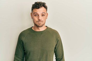 Günlük kıyafetler giyen genç İspanyol adam komik yüzlü yanakları şişiriyor. Havayla şişmiş ağız, çılgın bir ifade.. 