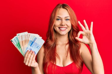 Güney Kore 'yi elinde tutan genç, güzel kızıl saçlı kadın banknotlar kazandı. Parmaklarıyla 
