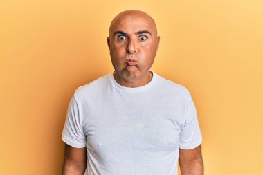 Normal beyaz tişört giyen olgun bir Orta Doğulu komik yüzlü yanak şişiriyor. Havayla şişmiş ağız, çılgın bir ifade.. 