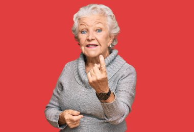 Kış süveteri giyen yaşlı, gri saçlı kadın seni çağırıyor. Gel buraya. Mutlu bir şekilde karşıla ve gülümse. 