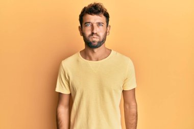 Sarı arka plan yanaklarını şişiren sarı tişörtlü, sakallı yakışıklı adam. Havayla şişmiş ağız, çılgın bir ifade.. 
