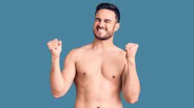 Mayo giyen genç yakışıklı adam çok mutlu ve heyecanlı, kollarını kaldırmış, gülümseyen ve başarı için çığlık atan kazanan bir jest yapıyor. kutlama konsepti. 