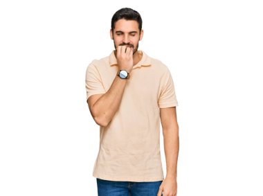 Günlük kıyafetler giyen genç İspanyol adam gergin ve gergin görünüyor. Ağzı tırnak yiyen eller. anksiyete. 