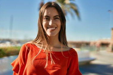 Genç İspanyol kadın gülümseyerek şehirde mutlu mesut dikiliyor..