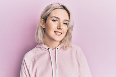 Mutlu ve havalı bir gülüşü olan sıradan kıyafetler giyen genç sarışın kız. şanslı kişi. 