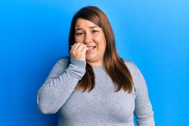 Güzel esmer, iri yarı, sıradan kıyafetler giyen, gergin ve elleri ağızda olan, tırnaklarını yiyen bir kadın. anksiyete. 