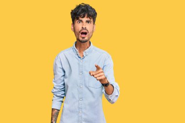 Gündelik kıyafetler giyen genç İspanyol adam kameraya kızgın ve sinirli bir şekilde seni işaret ediyor. 