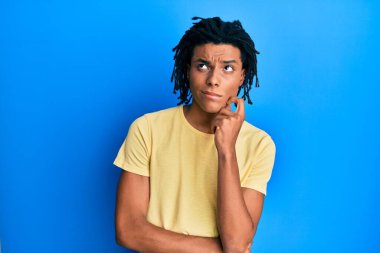 Genç, Afro-Amerikan bir adam günlük kıyafetler giyiyordu. Kuşku üzerine yoğunlaşmıştı. Parmakları çenesinde ve yukarı bakıyordu. 